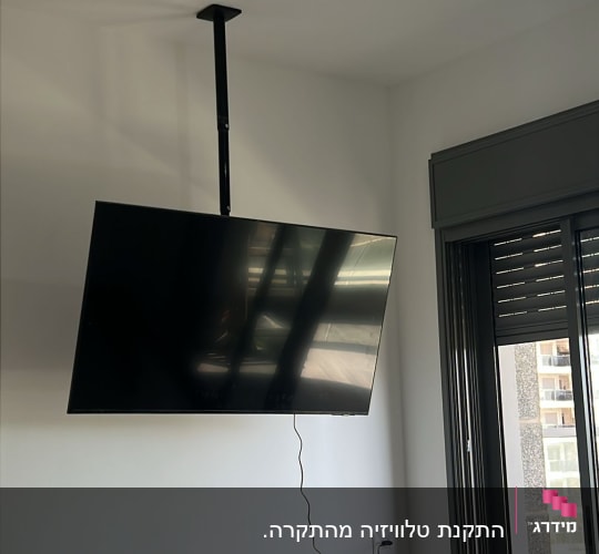 טלוויזיה תלויה על תקרה בחדר עם חלון